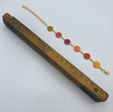 Bracelet réglable de 20 cm de longueur constitué de 6 médaillons de laiton et cuir (moutarde/fushia)